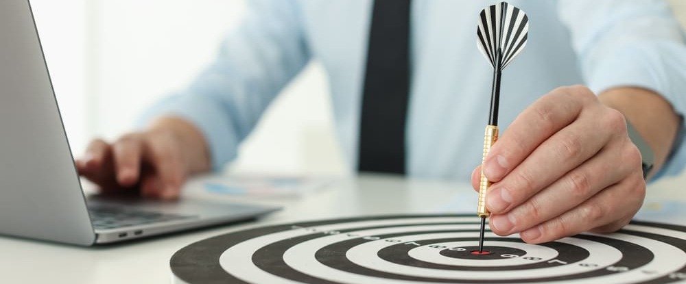 man with dart aiming at dartboard while working