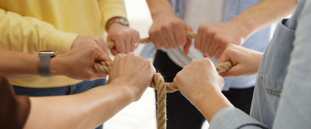 unity concept people holding rope together indoor